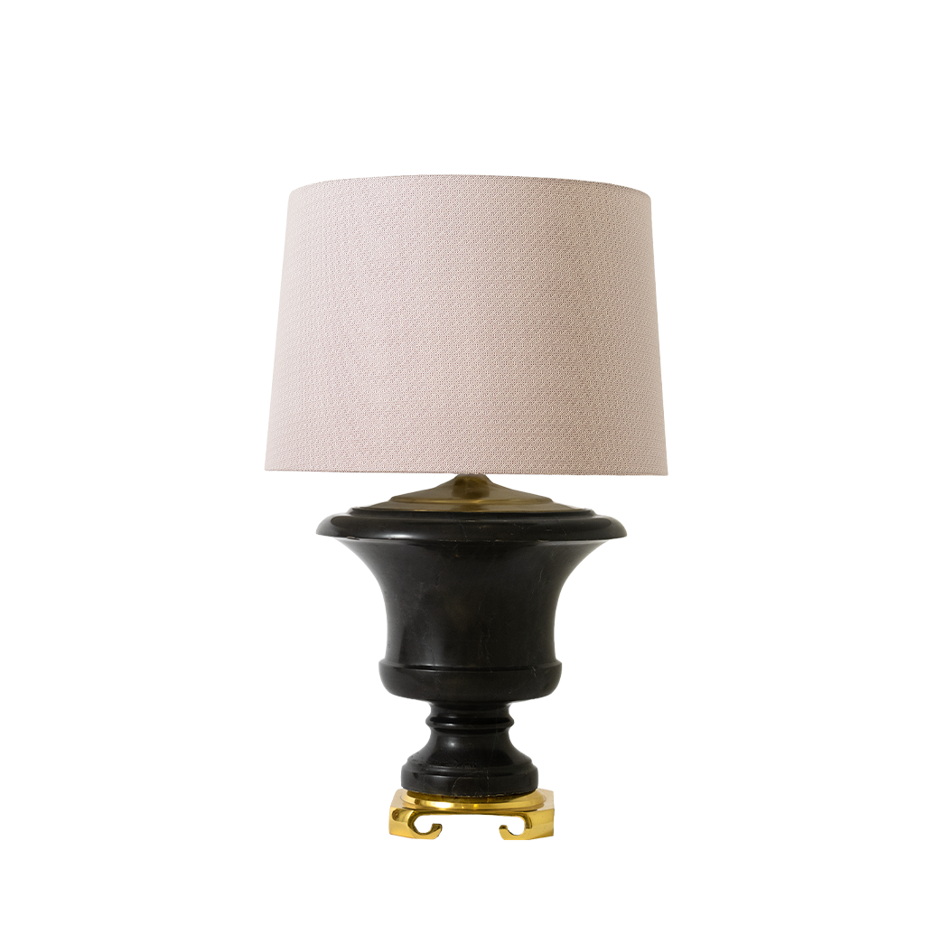 Table lamp with black base, gold foot, and beige lampshade on a white background