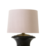 Lamp with a beige textured shade and black base on a white background