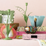 Decorative items including a vase, books, and a bowl on a surface with a light pink background.