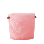 pink resin ice bucket with leather handles on a white background