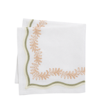 A folded white linen napkin with scalloped edges and embroidered leafy corner details in peach and olive green.