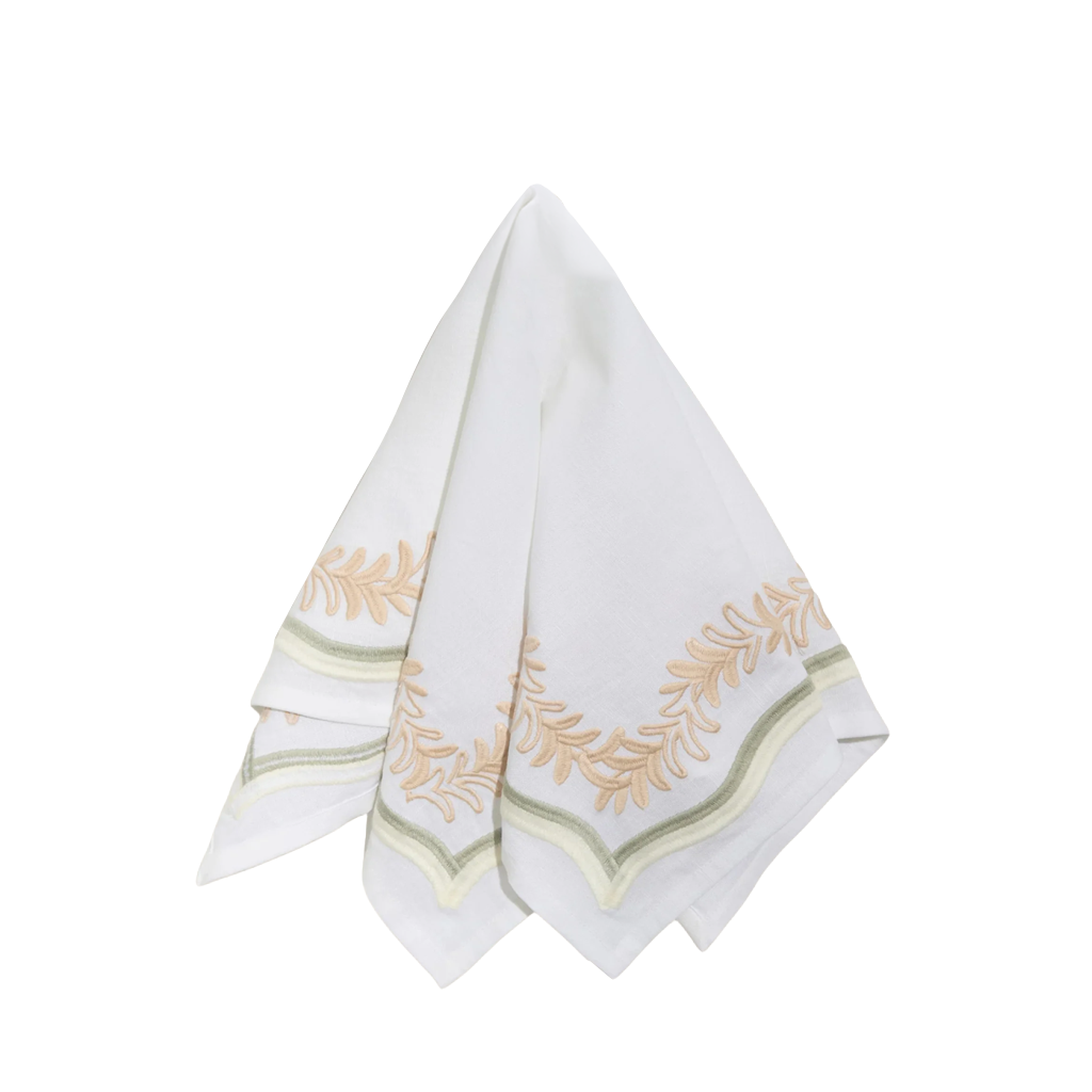 A white cotton napkin with embroidered gold and green leafy border details, folded and displayed on a solid white background.