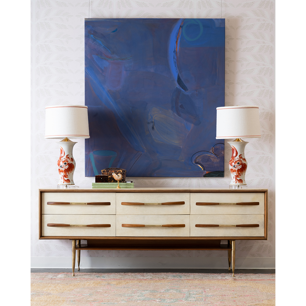 vintage sideboard with artwork and a white and orange lamps