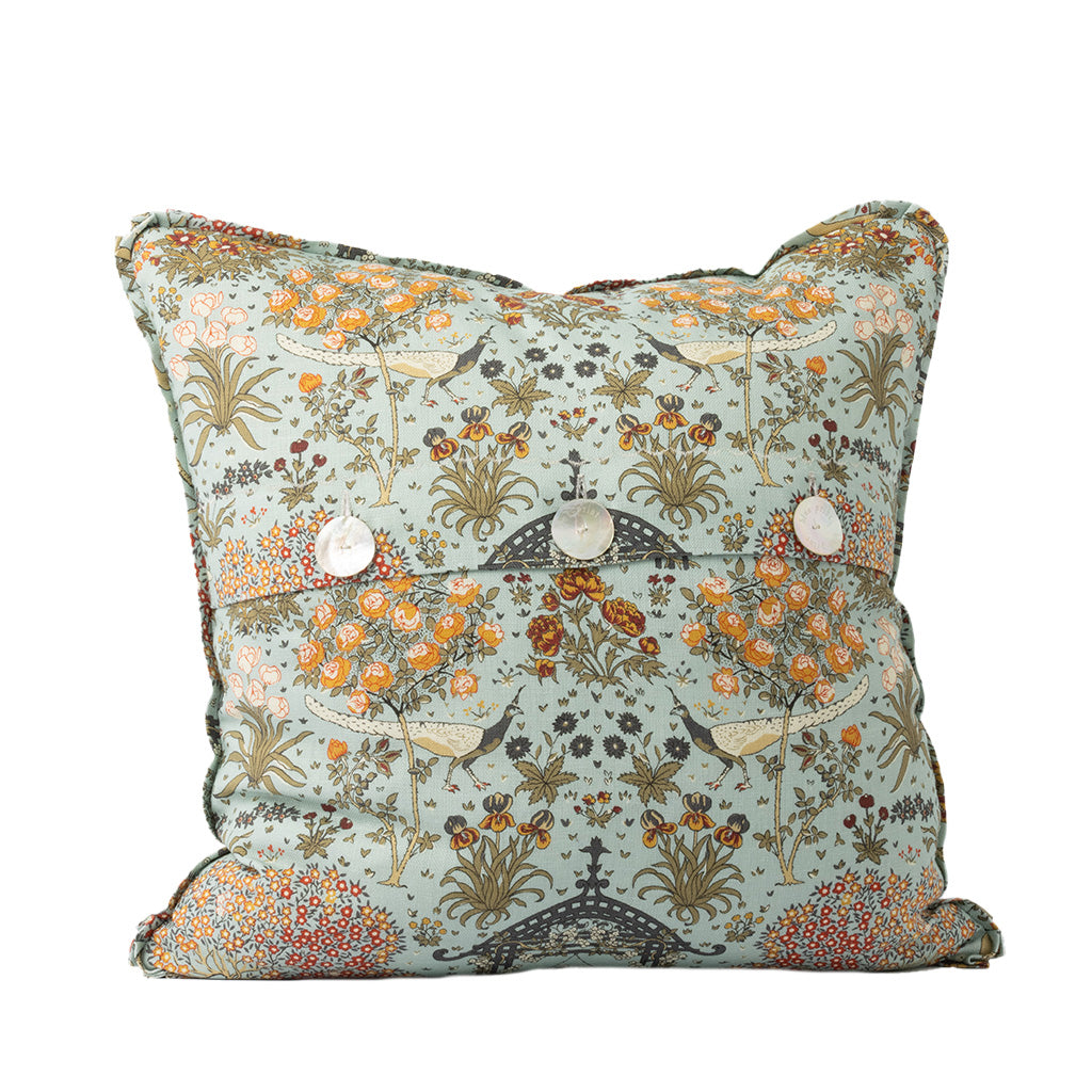 Back of a colorful pillow with a pagoda-like structure, birds, flowers, and botanicals with three mother of pearl button closures on a white background