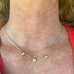 Gold necklace with small round pendants on a person wearing a red top.
