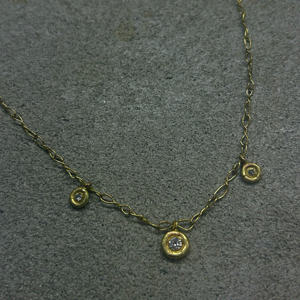 Gold necklace with small round diamond pendants on a gray surface