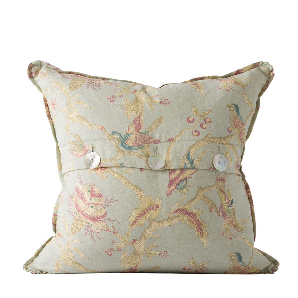Decorative pillow with floral and bird pattern on a white background