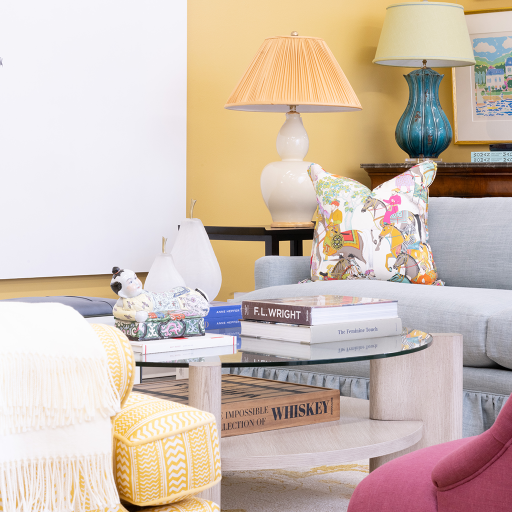 living room vignette with yellow walls decorated with lamps, pillows, books, and art