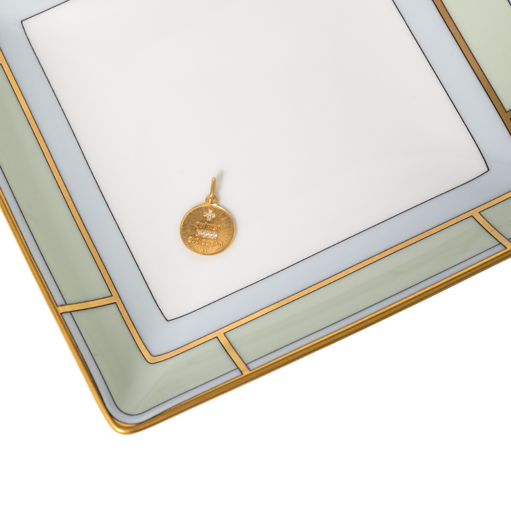 Gold pendant on a decorative tray on a white background