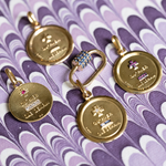 Gold charms with text on a purple patterned background