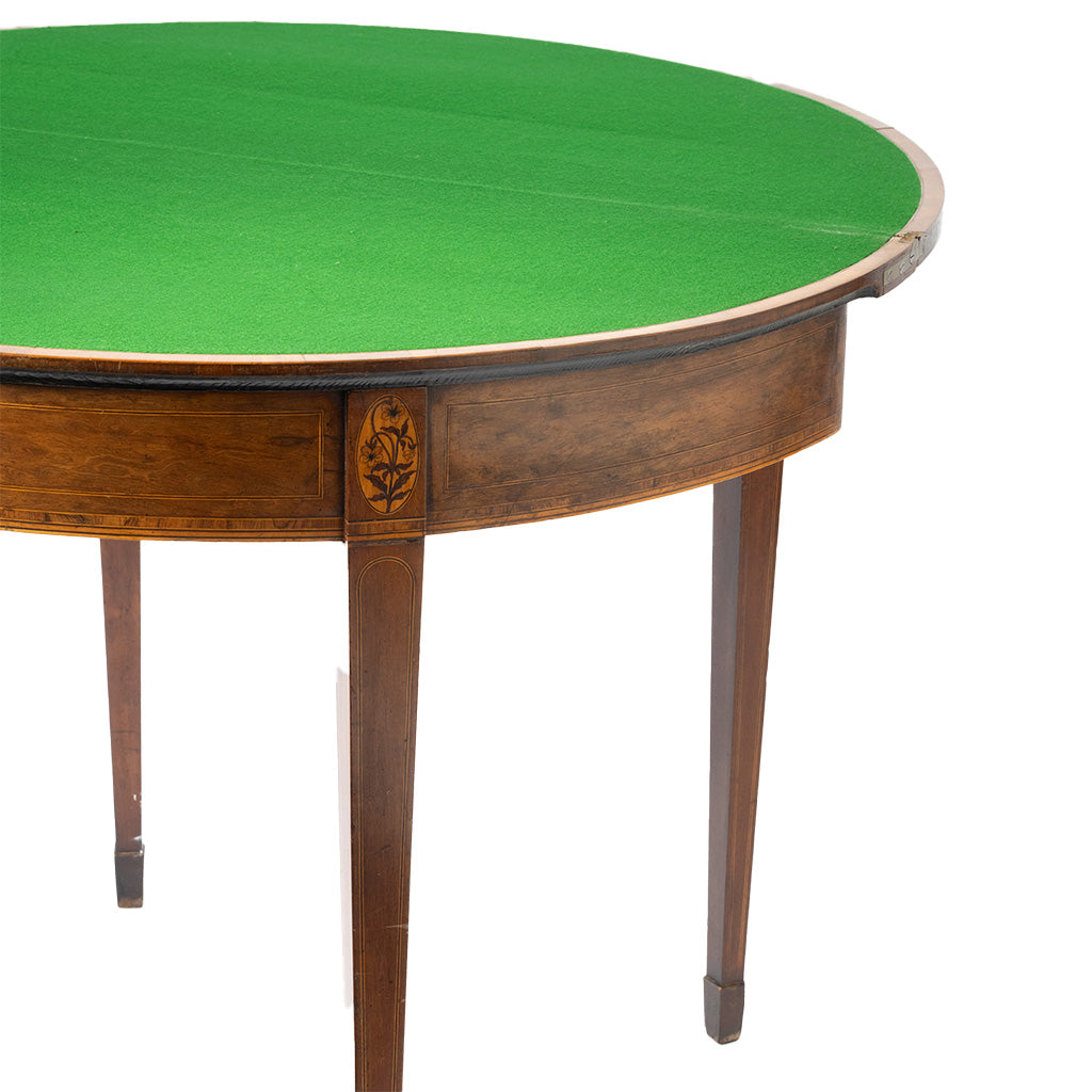 Close-up of a round wooden table with a bright green felt or turf top and dark brown legs, shown against a plain white background.