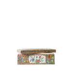 A rectangular ceramic box with a matching lid, decorated with a dense multicolor floral pattern and a central white panel showing painted figures and birds, set against a plain white background.