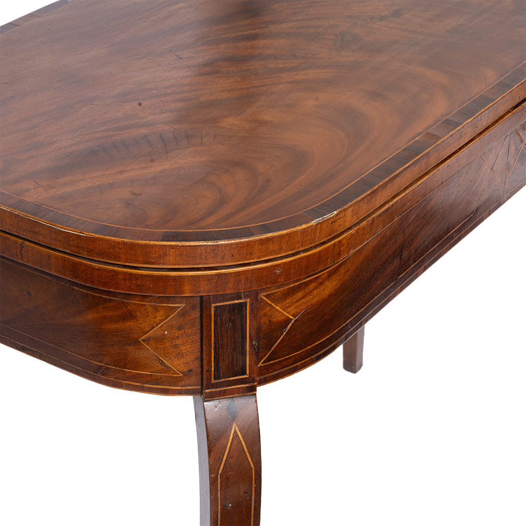 Close-up of a polished dark brown wooden table with curved edges, geometric inlay details, and a visible leg, photographed against a white background.