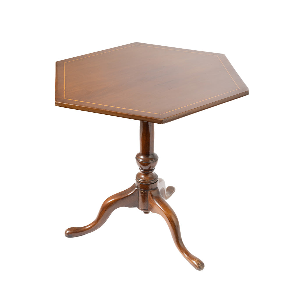 A hexagonal wooden pedestal table with a polished medium-brown finish and a three-legged tripod base, shown against a plain white background.