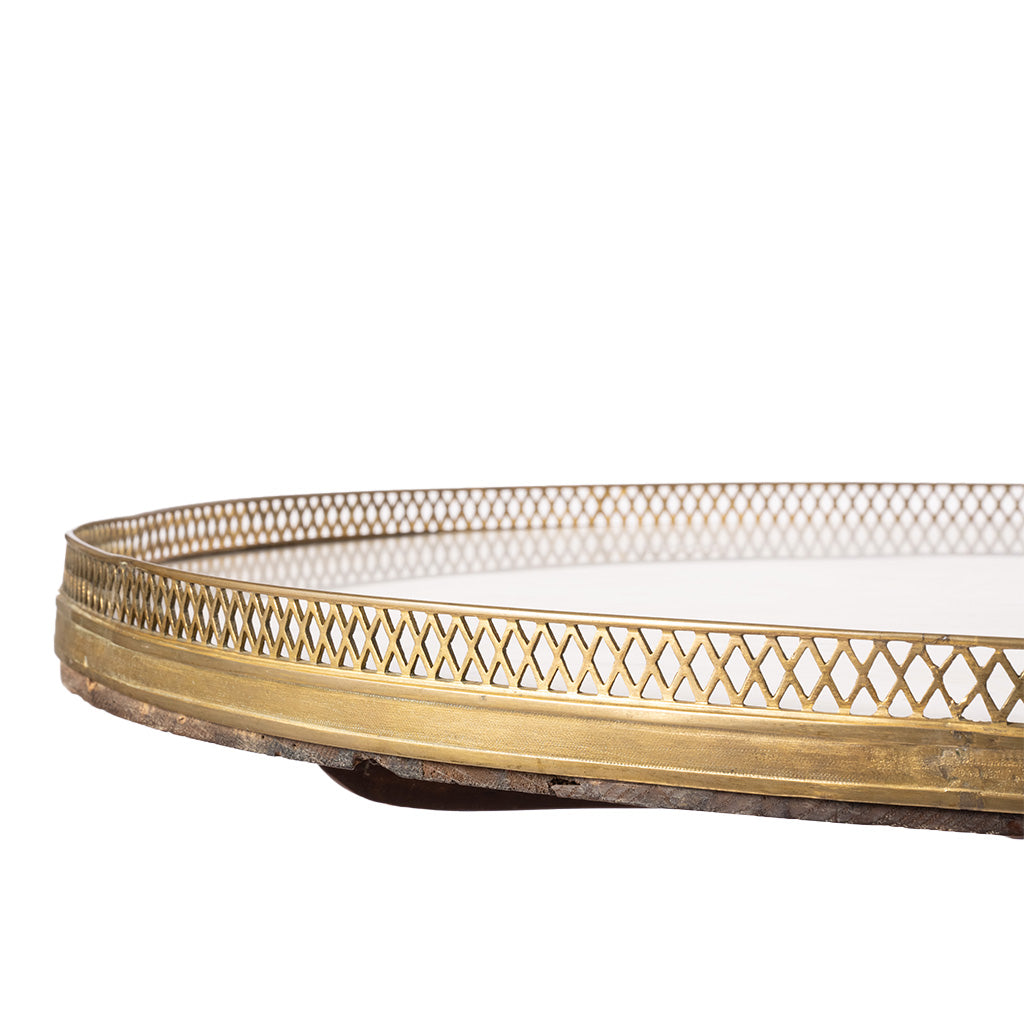Close-up of a round table featuring a polished gold brass frame with a decorative lattice pattern and a dark wood base, set against a plain white background.