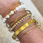 freshwater pearl bracelet 14k gold filled styled with other gold bracelets on a model's wrist