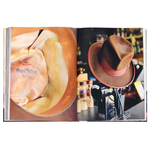 Open book showing a close-up of a bottle label and a hat on a stand.