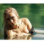 Woman with wet hair in a body of water wearing drop gold earrings and paperclip gold necklace with pendants