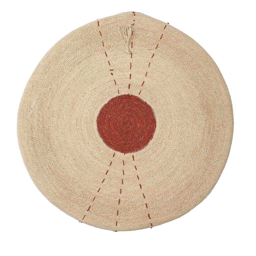 A round woven natural fiber tray with a central rust-red circle and radiating dashed line details, shown flat against a white background.