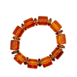 A beaded stretch bracelet featuring polished amber-orange cylindrical beads separated by small metallic spacer rings, shown on a plain white background.