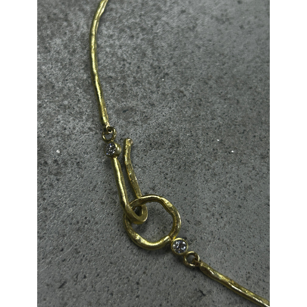 Close up of Gold necklace with decorative elements on a gray surface