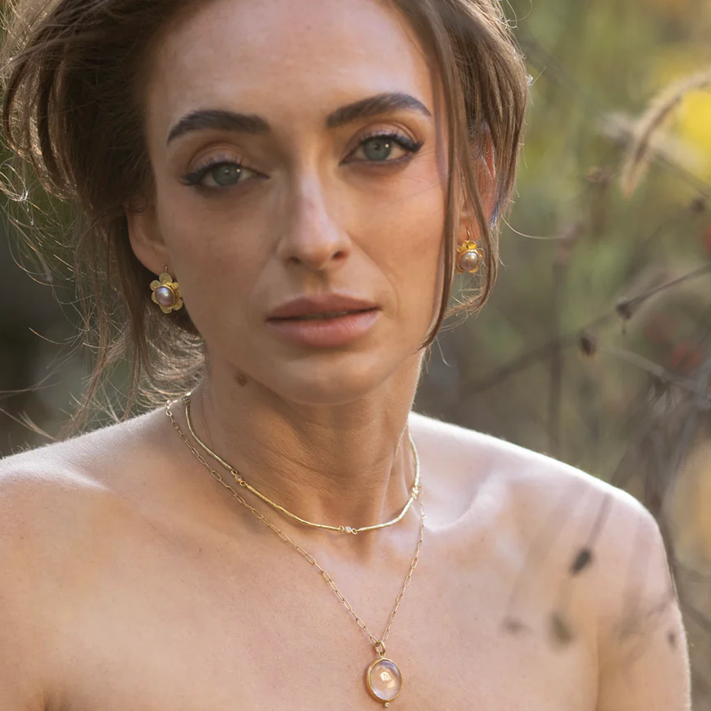Woman wearing gold jewelry with a blurred natural background