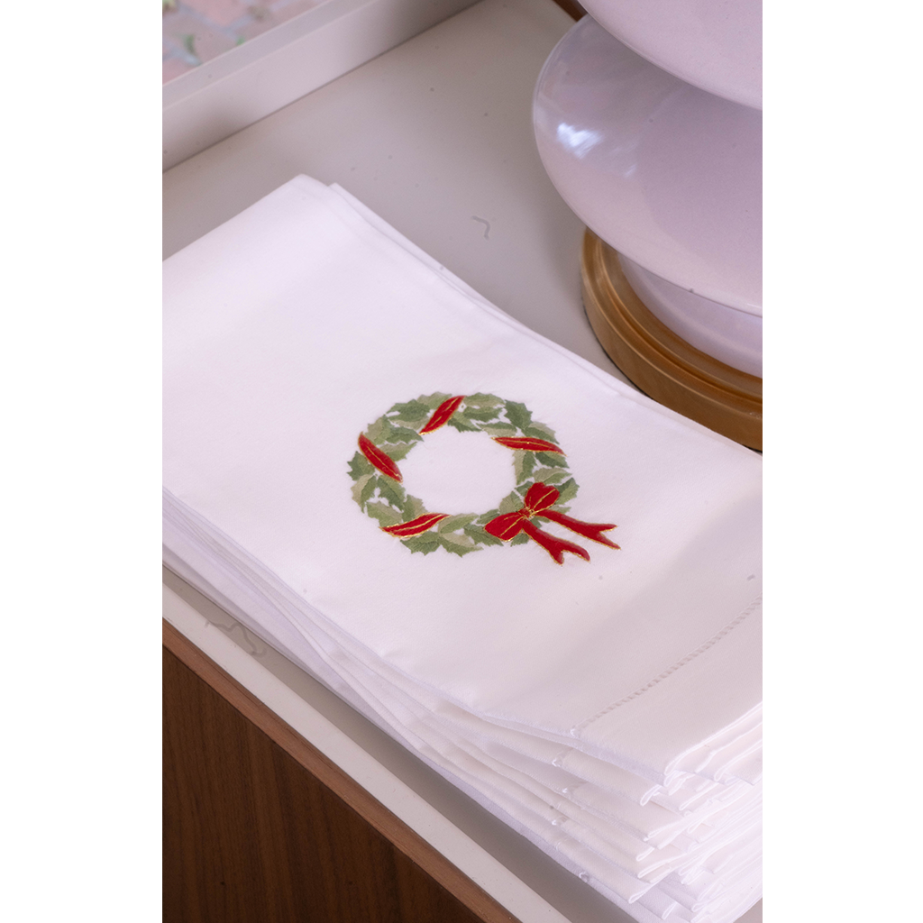 White tea towel with green holly wreath with red ribbon 