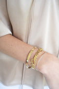 Gold name bracelet on model with additional bracelets