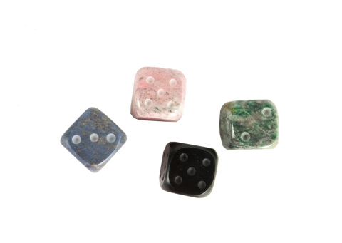 An aerial view of andean stone dice, set of four. Each dice is a different color: pink, blue, green, black