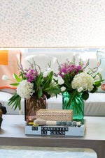 Small Natural Rattan Accent Box, styled on coffee table with books, calligraphy brush, and floral arrangements