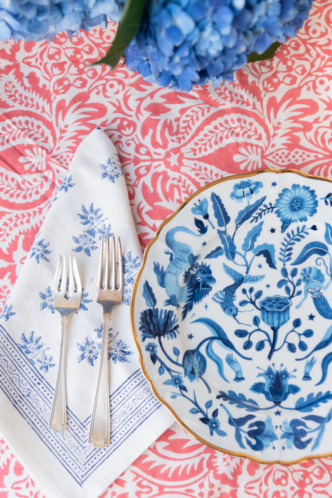Close up view of Jasmine Blue Napkin with flatware and dinner plate on top of tablecloth