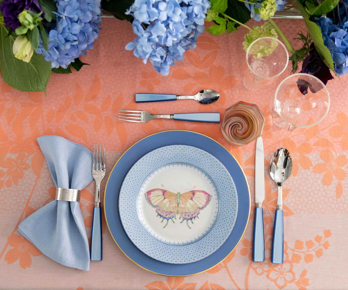 Sabre Paris Icone Flatware in Sky displayed with accent plate, dinner plate, napkin and glassware on top of tablecloth