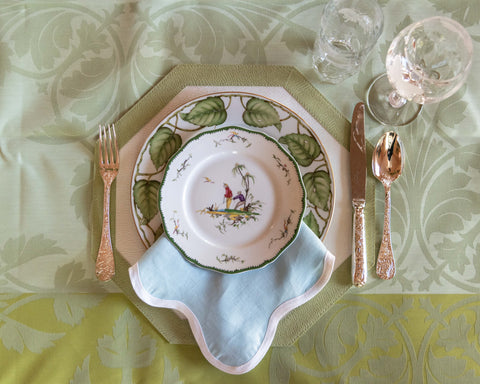 Birds eye view of Christofle Jardin D'Eden Flatware displayed with accent plate, napkin, dinner plate, tablecloth and glassware on top of tablecloth