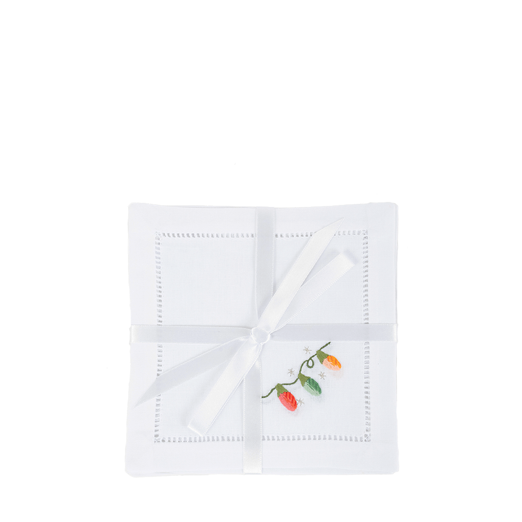 white cocktail napkins with green, red, and orange Christmas lights embroidered in bottom right corner