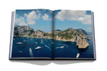 Yachts: The Impossible Collection book open and showing photo of yachts in open water with scenic cliffside beach